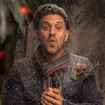 A man wearing a scarf and jacket stands in a snowy landscape, surrounded by a serene winter scene.